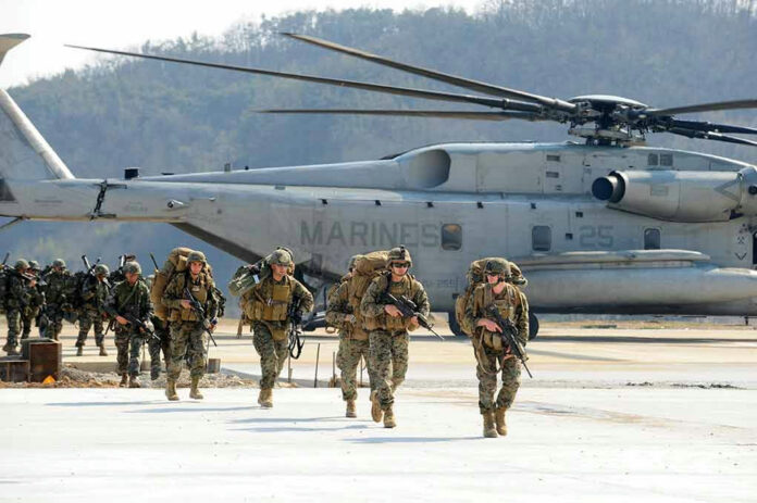 1123252001 Soldiers walk past military helicopter on airfield.