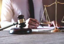 Gavel and scales beside a person writing.