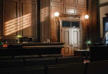 Supreme Showdown: Elites Eye The Gavel Empty courtroom with sunlight streaming through windows.