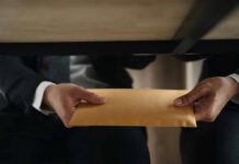 Trump Jr.–Adani: Then Charges Disappear Two people exchanging an envelope under a table.