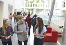 Campus Group Honors Firebomber Students conversing in bright school hallway.