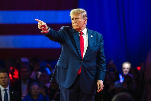 Man in suit pointing on a stage.