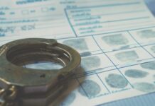 Handcuffs resting on a fingerprint card with inked fingerprints