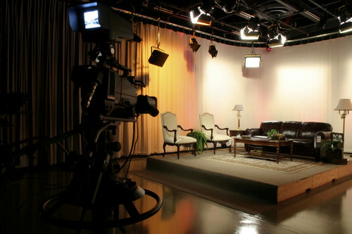 Empty TV studio set with chairs and a sofa.
