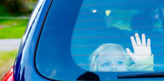 Child waving from the back window of car.