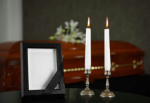 Lit candles, empty frame, and a casket in background.