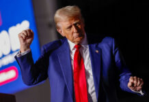Man in blue suit with red tie speaking