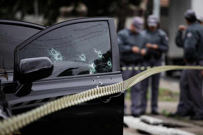 Car door with bullet holes at a taped-off crime scene