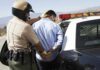 Police officer arresting a suspect near a patrol car