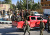 September Ultimatum — Will Guns Go Quiet? Group of soldiers in military gear gathered around a red pickup truck in an urban setting