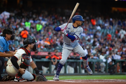 A baseball player from the Dodgers prepares to bat while the catcher is in position