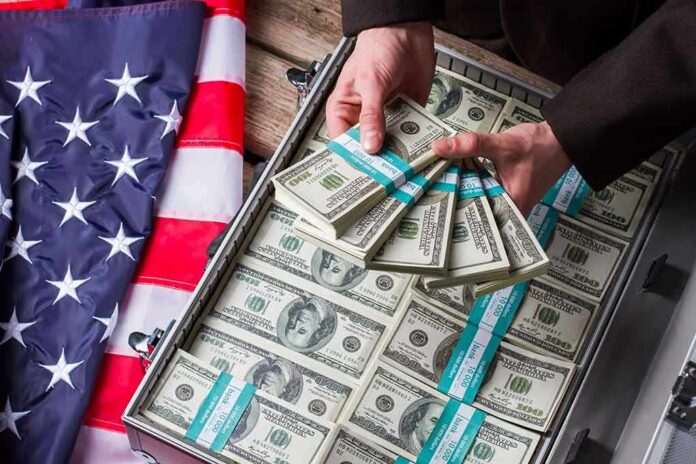 Hands holding bundles of US $100 bills over a briefcase of cash