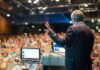 Mao Suit Meltdown Jolts Dem Convention Speaker presenting to a large audience in an auditorium