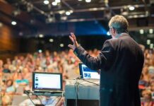 Mao Suit Meltdown Jolts Dem Convention Speaker presenting to a large audience in an auditorium