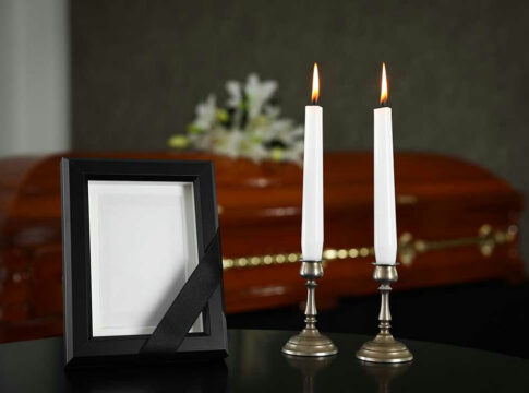 Lit candles, empty frame, and a casket in background.