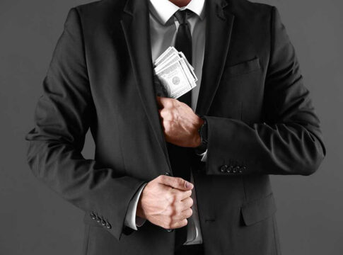 Man in suit hiding stacks of money.