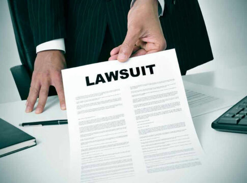 Holding a document titled Lawsuit in an office.