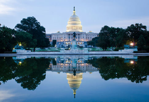 United States Capitol building reflected in a calm pool at dusk