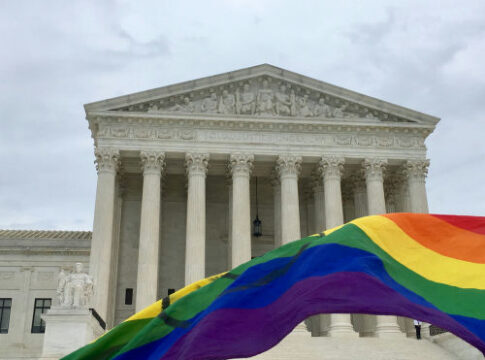Supreme Court building with rainbow flag in foreground.