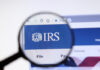 Magnifying glass focusing on IRS logo on a website.