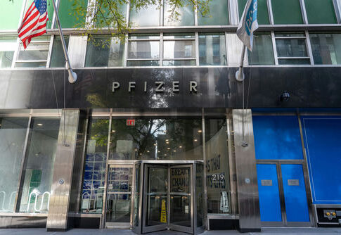 Pfizer headquarters building entrance with glass doors and flags.