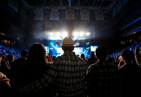 Audience at a concert with a person in a cowboy hat in the foreground