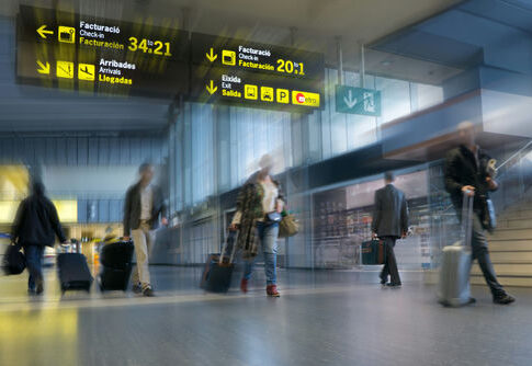 Travelers with rolling suitcases walk through an airport terminal