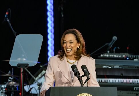Woman in a light-colored blazer speaking at a podium