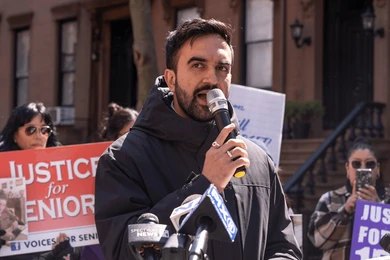 Man speaking into a microphone at an outdoor rally